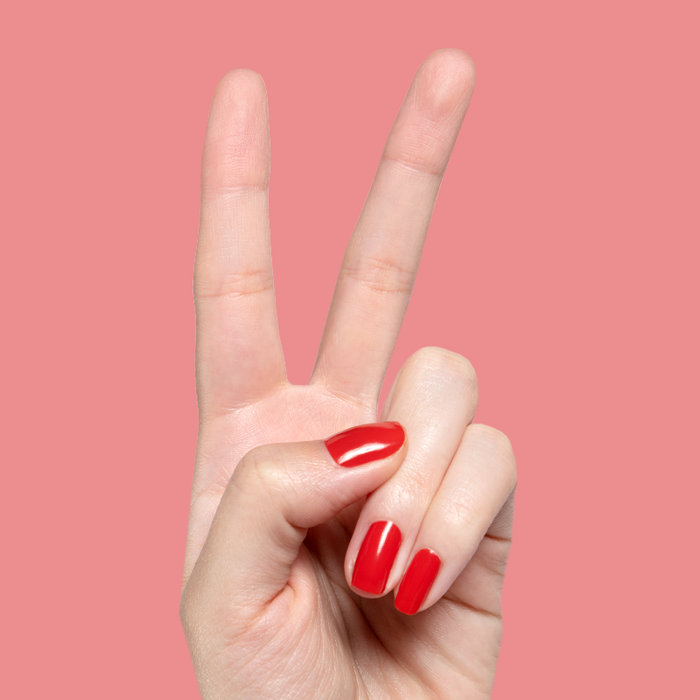 Hand showing bright glossy Let’s Circle Back gel polish manicure in vibrant orange-red on soft pink background