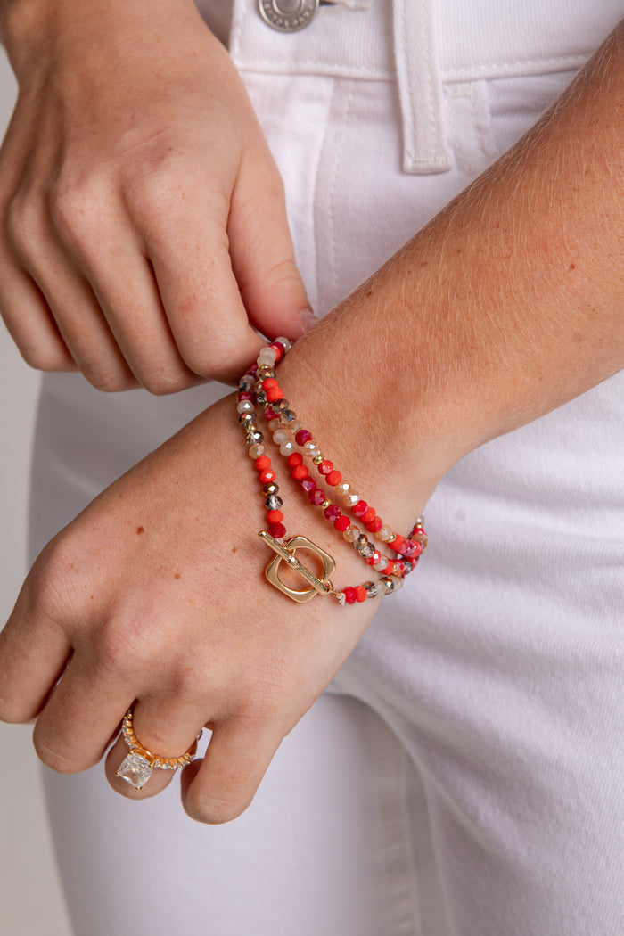 Person adjusting a bracelet on their wrist with a plain background