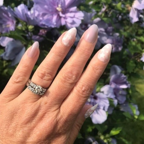 Hand showing Mermaid Stars - Press-On | Medium | Almond nails with soft neutral base and subtle star designs outdoors