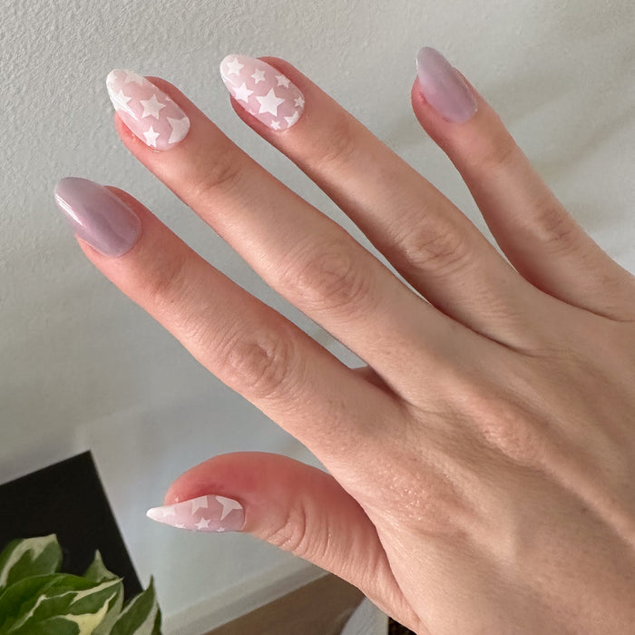 Hand showing Mermaid Stars - Press-On | Medium | Almond nails with iridescent purple and white star design for easy at-home mani