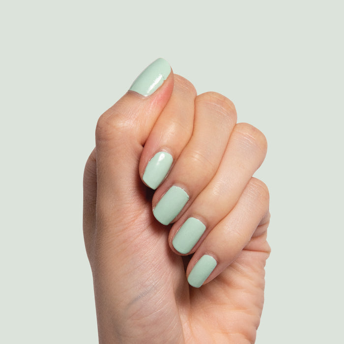 Hand displaying nails painted in pastel mint green Minty polish for a fresh, at-home manicure by Olive and June