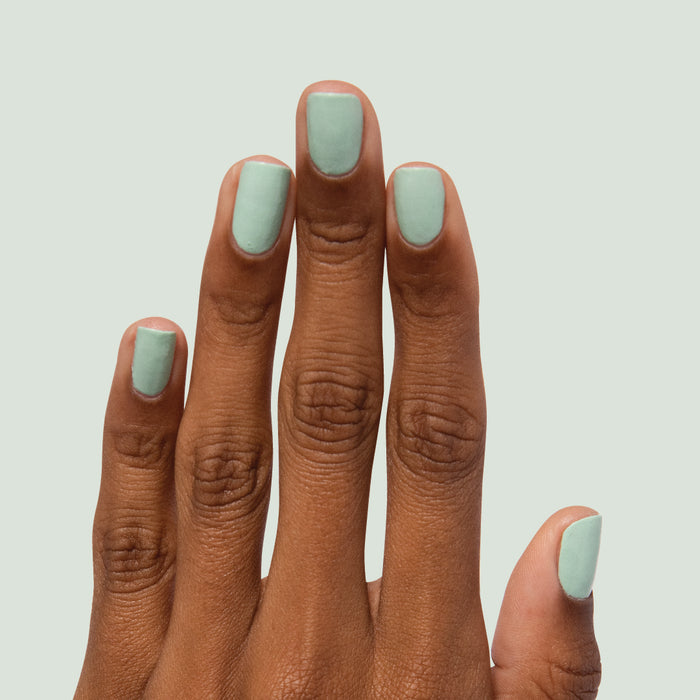 Hand with nails painted in pastel mint green Minty for a smooth, refreshing at-home manicure by Olive and June