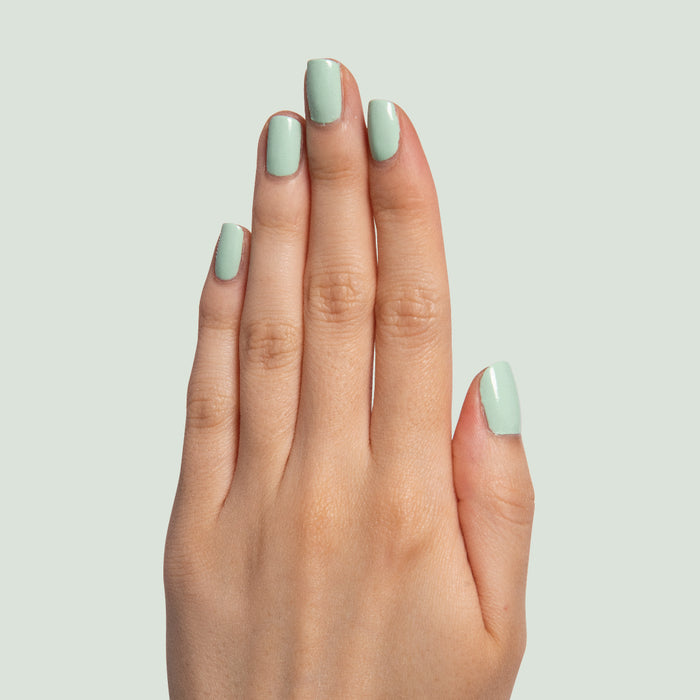 Hand displaying nails painted in pastel mint green Minty polish for a fresh manicure by Olive and June