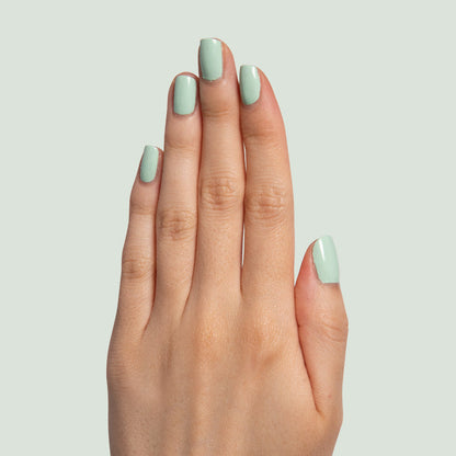 Hand displaying nails painted in pastel mint green Minty polish for a fresh manicure by Olive and June