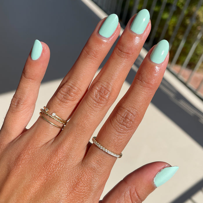 Hand featuring nails painted in pastel mint green Minty polish for a smooth, fresh manicure at home