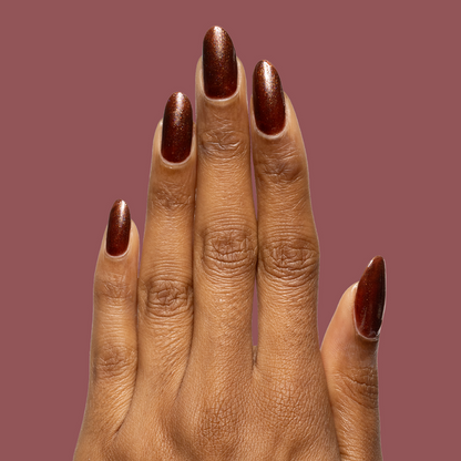 Hand with long oval nails painted deep shimmery chocolate brown Museum Date gel polish against muted mauve background
