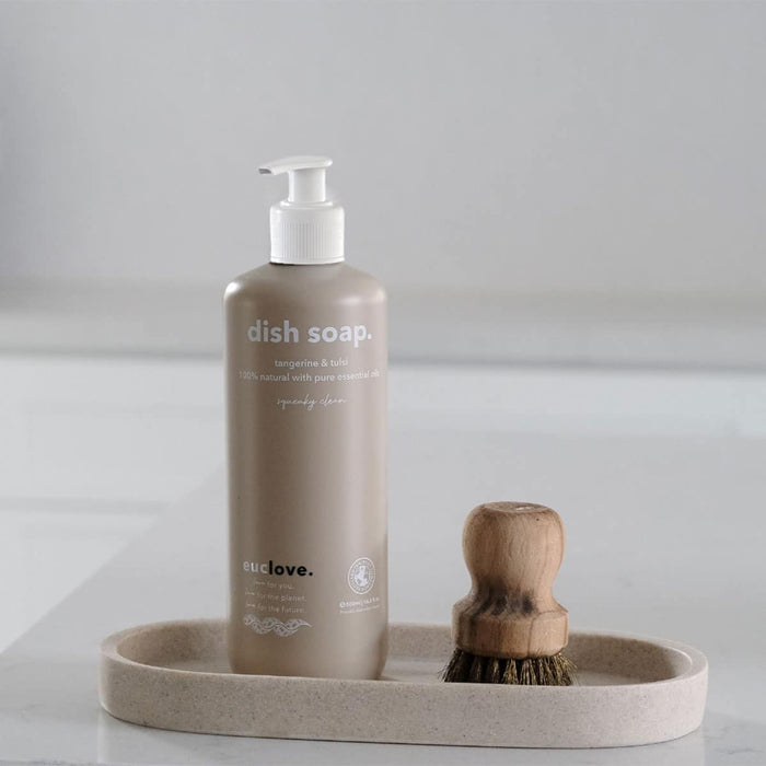 Brown Euclove dish soap 500ml bottle with pump and wooden brush on a beige tray against a light gray background.