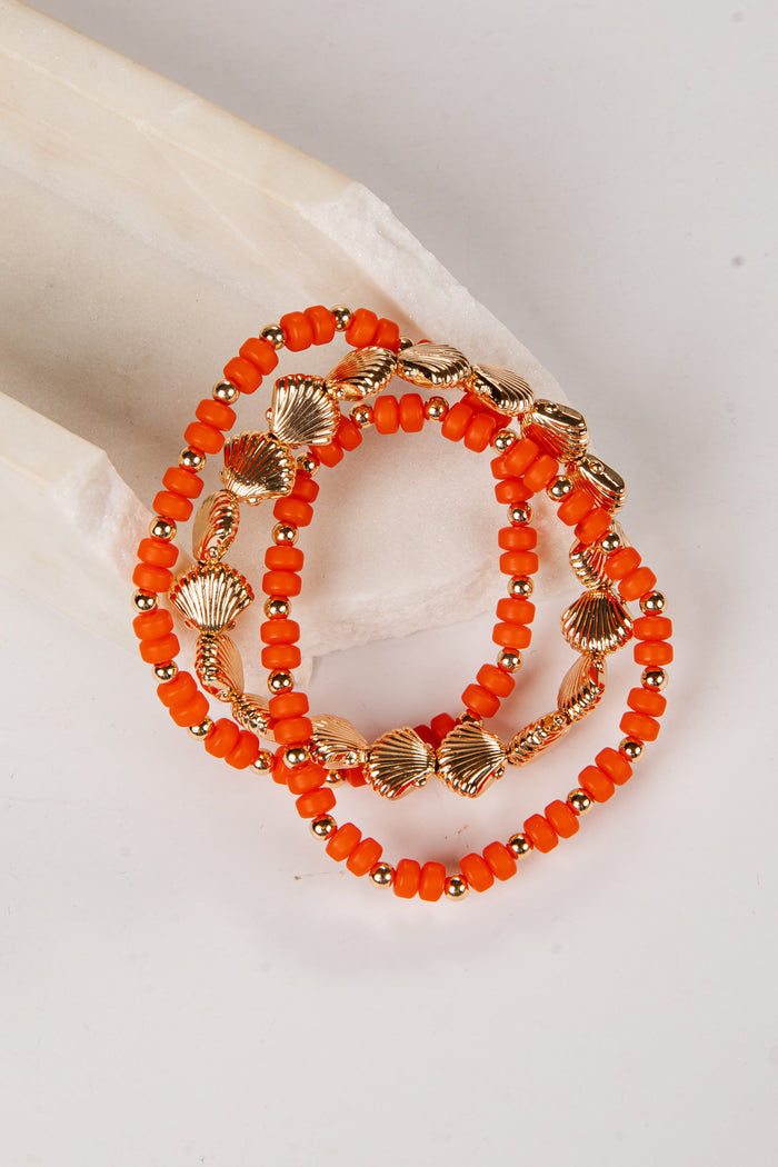 Orange beaded bracelet with gold accents on a light background