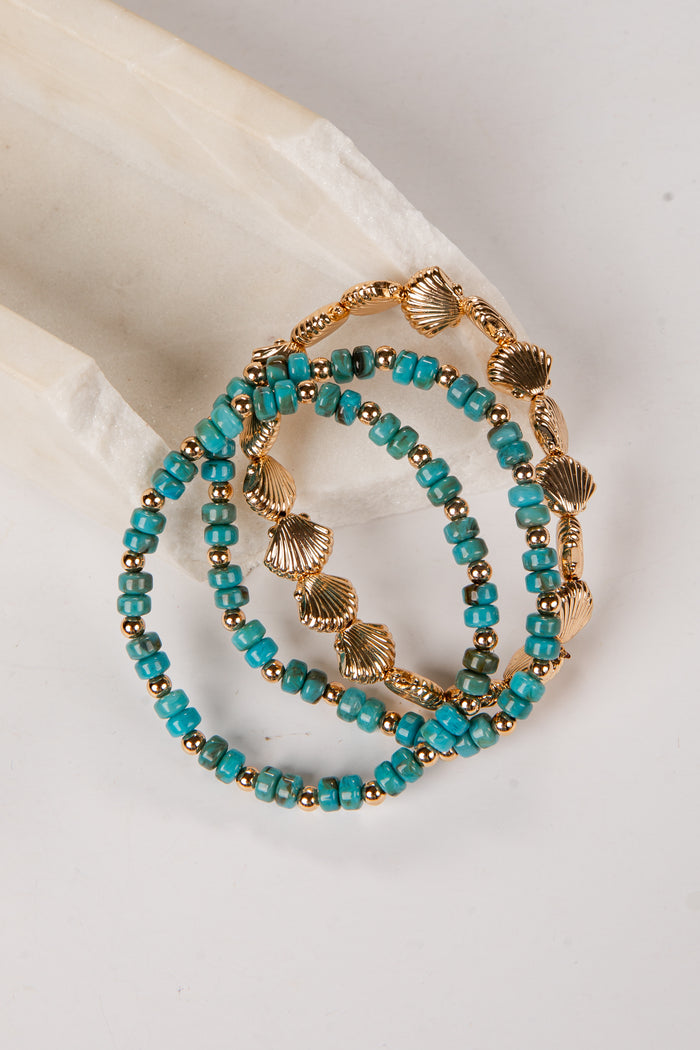 Turquoise beaded bracelet with gold accents on a white surface