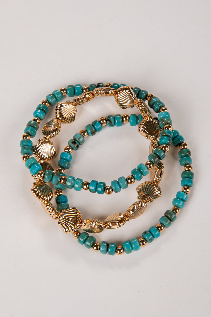 Two turquoise beaded bracelets with gold accents on a light gray background