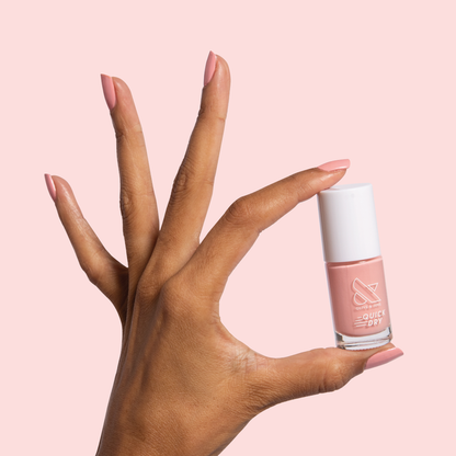 Hand holding a bottle of Nuance polish with nails coated in medium bubblegum pink for a quick dry mani look