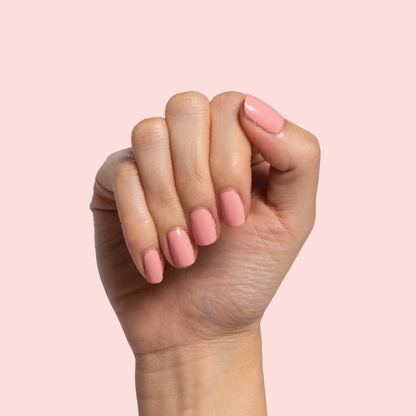 Hand with nails painted in Nuance medium bubblegum pink polish for a smooth and polished at-home manicure look