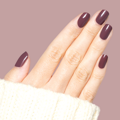 Hand with medium-length nails coated in Patron of the Arts dusty deep rose brown gel polish against soft mauve background
