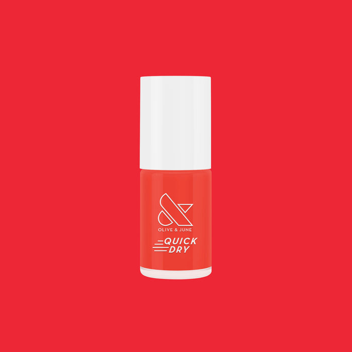 Olive and June Picante quick dry nail polish bottle in bright orangey red on solid red background for mani display