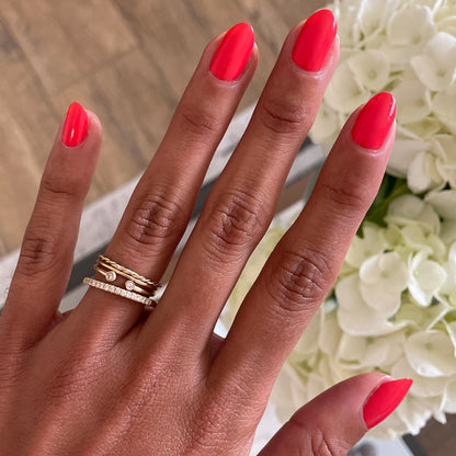 Hand with nails painted in bright orangey red Picante polish displayed against white flowers for manicure showcase
