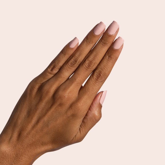 Hand with perfectly manicured nails painted in Pointe classic ballerina pink polish for an elegant at-home mani look