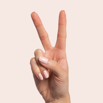 Hand showing peace sign with nails polished in Pointe soft ballerina pink for a polished at home mani look