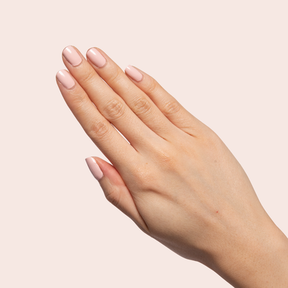 Hand with nails painted in Pointe soft ballerina pink polish for a classic, elegant at-home manicure look.