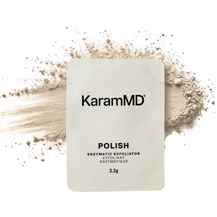 A KaramMD Polish enzymatic exfoliator sachet in a light beige pouch, centered over a scattered powder spill on a white background.