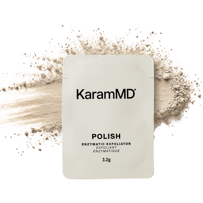 A KaramMD Polish enzymatic exfoliator sachet in a light beige pouch, centered over a scattered powder spill on a white background.