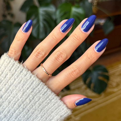 Hand with glossy deep navy blue Power Suit gel polish on long almond-shaped nails against indoor background