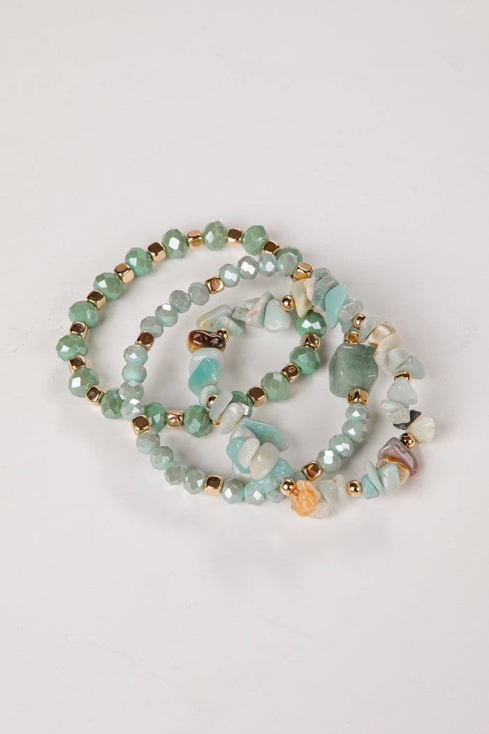 Beaded bracelets with green and gold beads on a light gray background