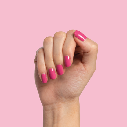 Hand with neatly shaped nails painted in Prom bold magenta pink polish for a vibrant at-home manicure look