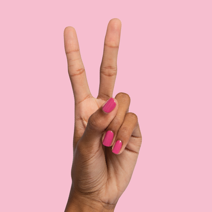 Hand showing a peace sign with nails painted in Prom bold magenta pink for a vibrant at-home manicure look
