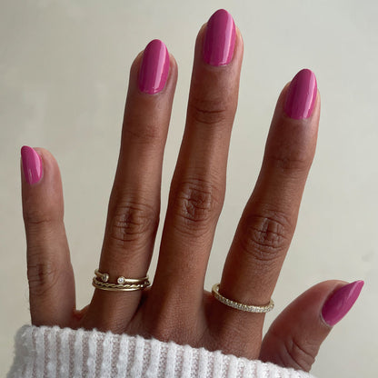 Hand with almond-shaped nails painted in Prom bold magenta pink polish for a glossy at-home manicure look
