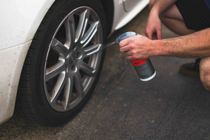 Person spraying KochChemie Reactive Rust Remover on a car tire rim.