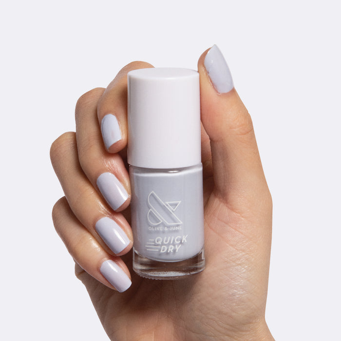Hand holding Rink quick dry polish bottle with nails painted in icy pastel blue for a fresh mani look