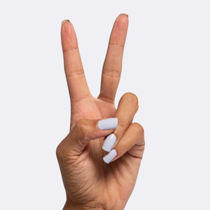 Hand showing peace sign with nails painted in icy pastel blue Rink quick dry polish for at-home manicure