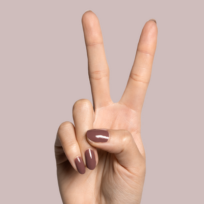 Hand with light skin tone wearing Shacket warm rose neutral gel polish for a smooth, long-lasting manicure on pink background