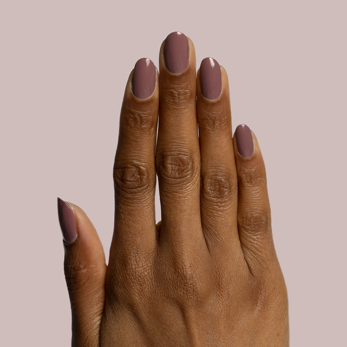 Hand with warm medium skin tone wearing Shacket gel polish in warm rose neutral for a sleek manicure on mauve background