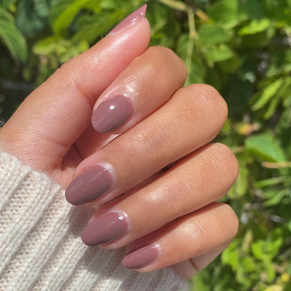 Hand with medium warm skin tone wearing Shacket gel polish in warm rose neutral for a smooth, long-lasting manicure outdoors