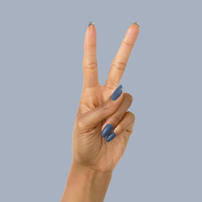 Hand displaying peace sign with Social Studies polish in deep sun-bleached navy on glossy nails against a muted background