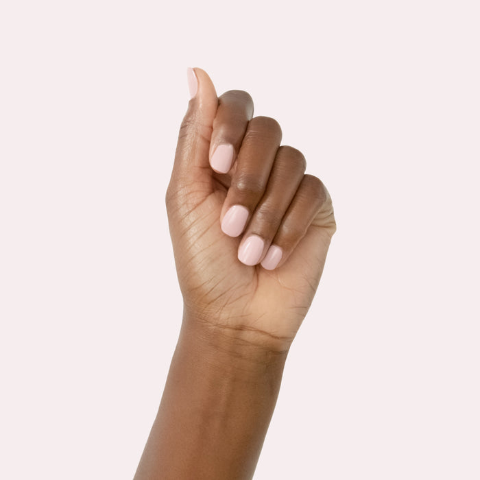 Hand with neatly manicured nails in vintage rose pink using Study Hall long-lasting polish on pale pink background