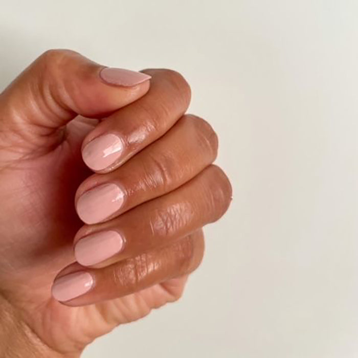 Hand with glossy, smooth manicure in Study Hall vintage rose pink polish on neutral background