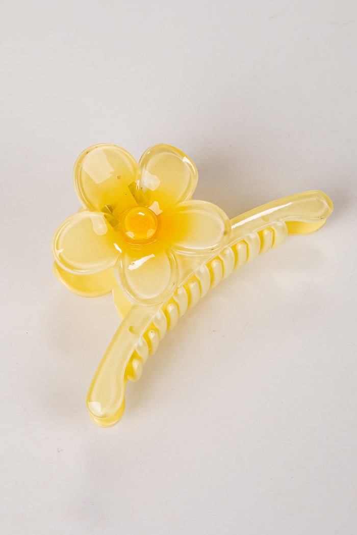 Yellow flower-shaped hair clip on a light gray background