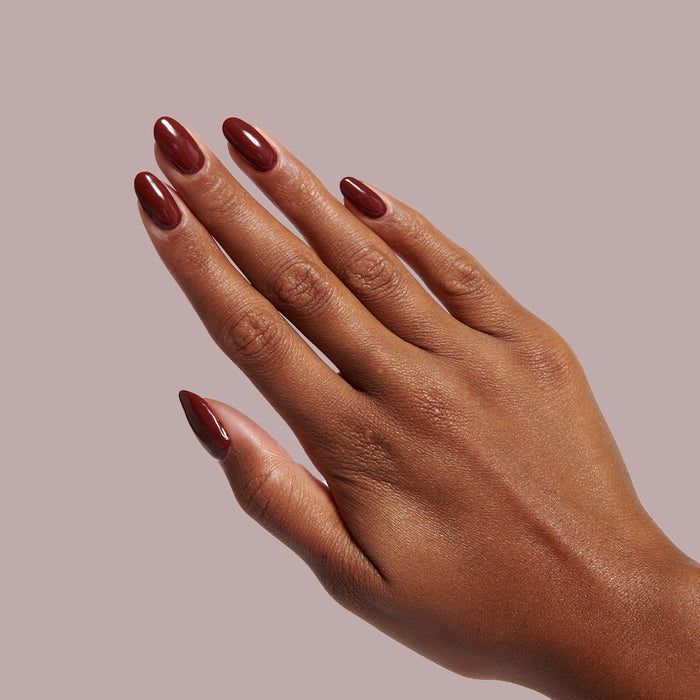 Hand with deep maroon manicure using Team Spirit nail polish for a long-lasting and polished at-home mani look