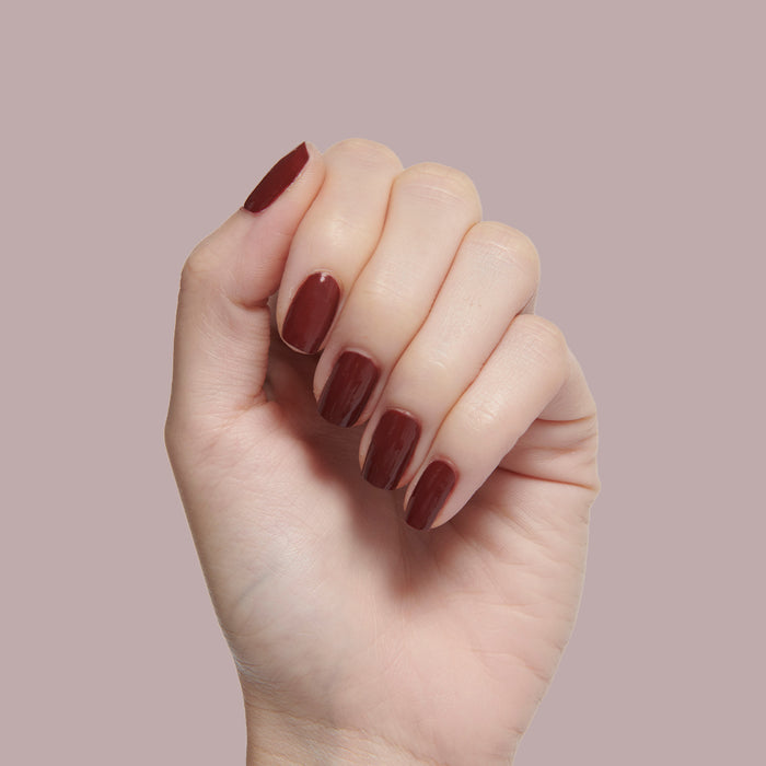 Hand showcasing a deep maroon manicure with Team Spirit polish for a smooth, long-lasting at-home mani look