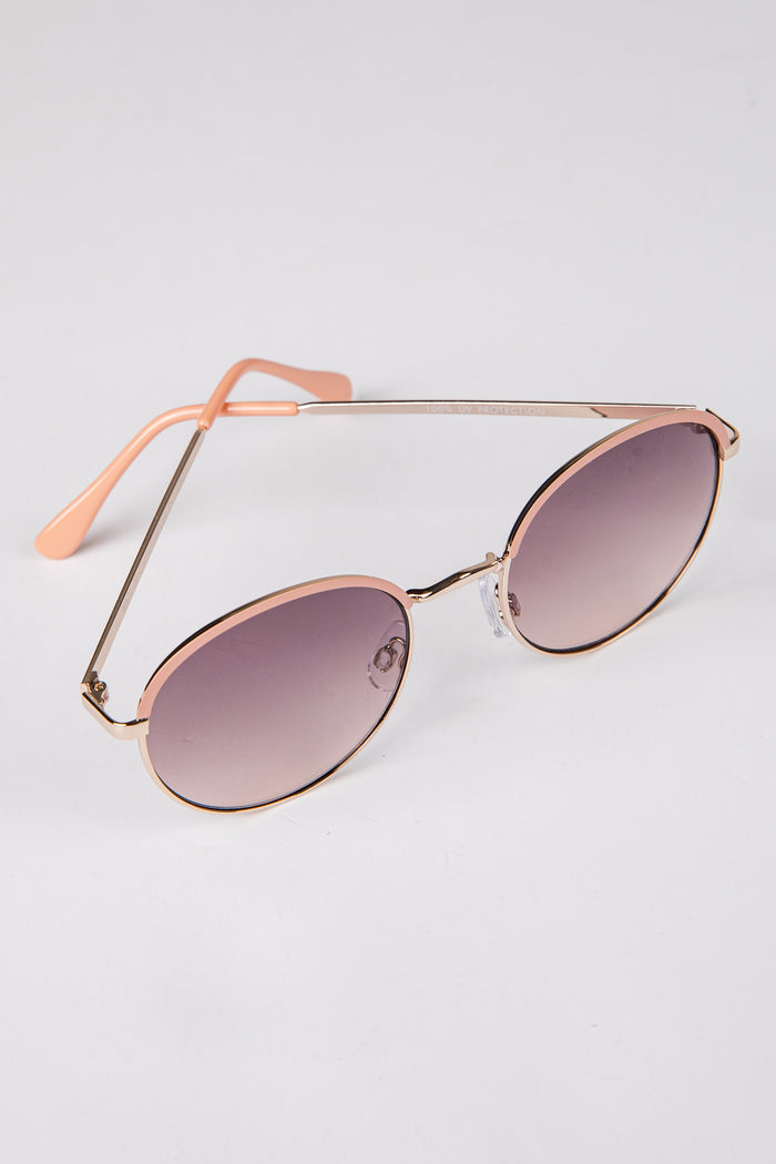 Sunglasses with rose gold frame and gradient lenses on a light gray background