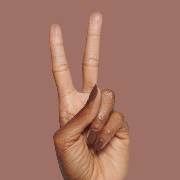 Tip Your Barista long-lasting polish on neatly manicured nails showing a peace sign against a brown backdrop
