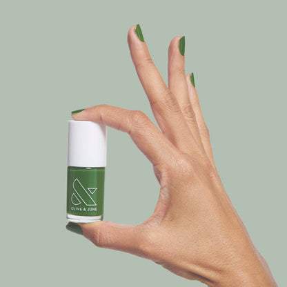 Hand with medium-length nails painted in fresh turf green Touchdown! nail polish by Olive and June for a chic mani