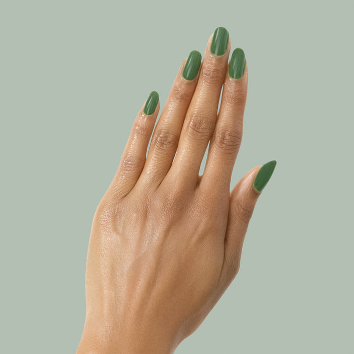 Hand with almond-shaped nails coated in Touchdown! polish, a fresh turf green for a smooth, long-lasting mani by Olive and June
