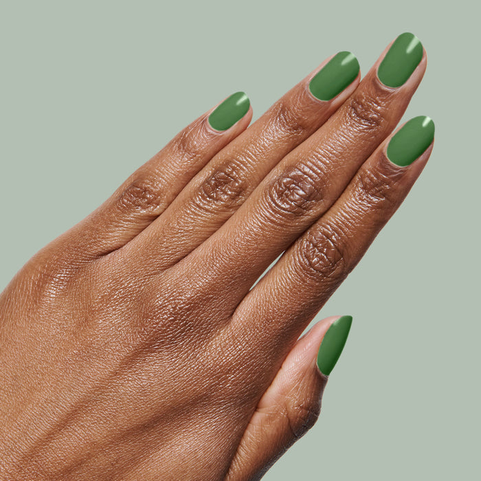 Hand with medium-length nails painted in fresh turf green Touchdown! polish for a smooth, long-lasting manicure by Olive and June