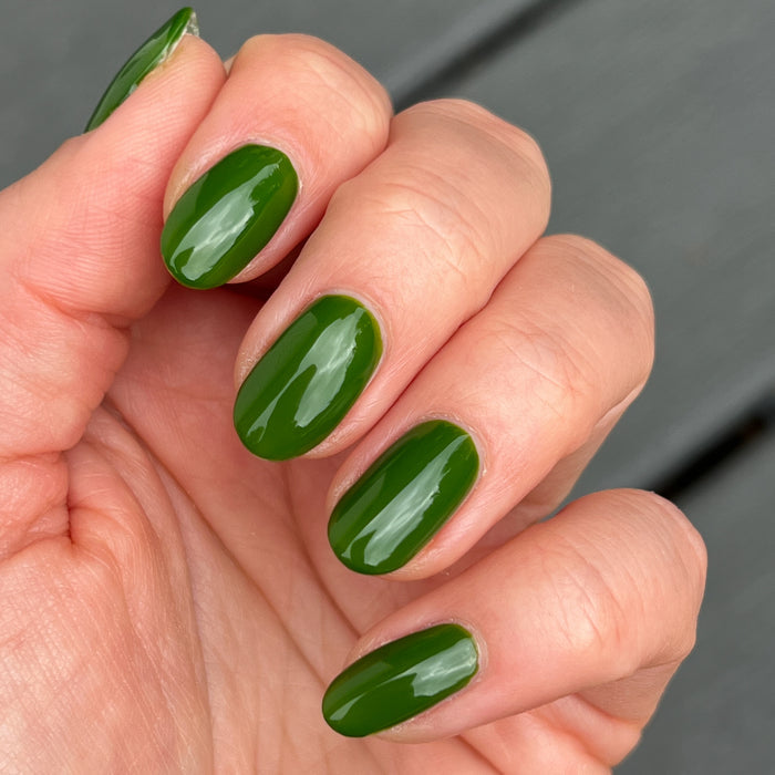 Hand with glossy medium-length nails painted in Touchdown! polish, a fresh turf green for a durable manicure