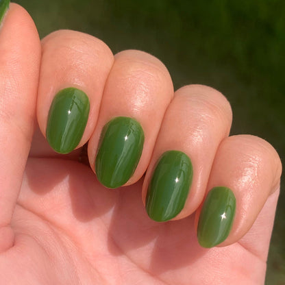 Hand with glossy oval nails painted in Touchdown! polish, a fresh turf green for a smooth, long-lasting mani