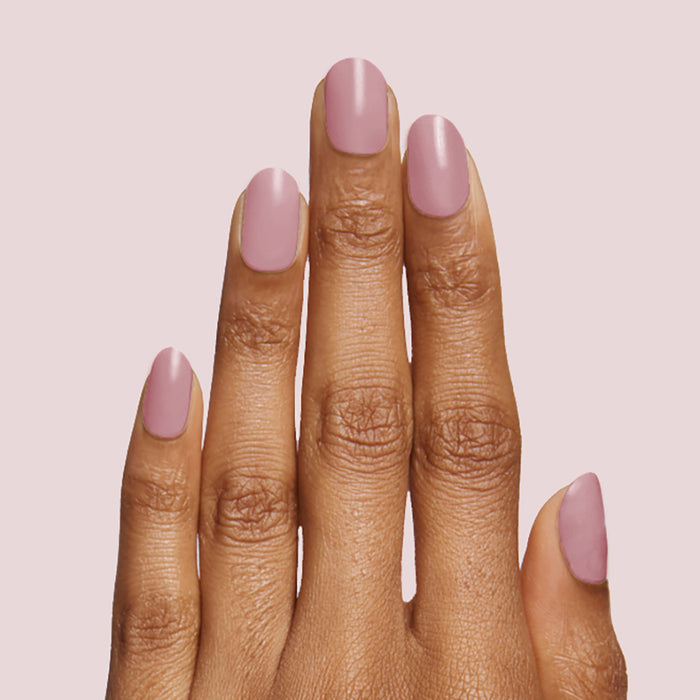 Hand with smooth mauve manicure featuring World Lit nail polish on neutral pink background