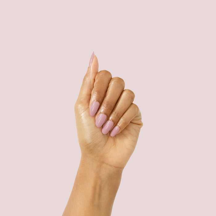 Hand with glossy mauve manicure showcasing World Lit polish against a soft pale pink background